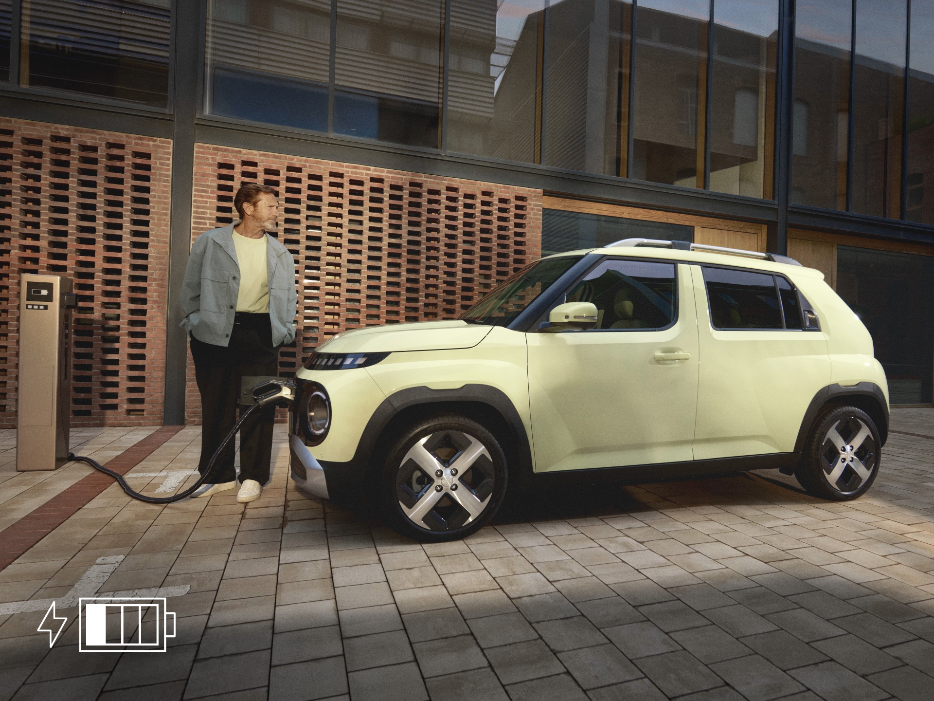 Person stands next to the INSTER while it charges at a public charging station in an urban plaza.